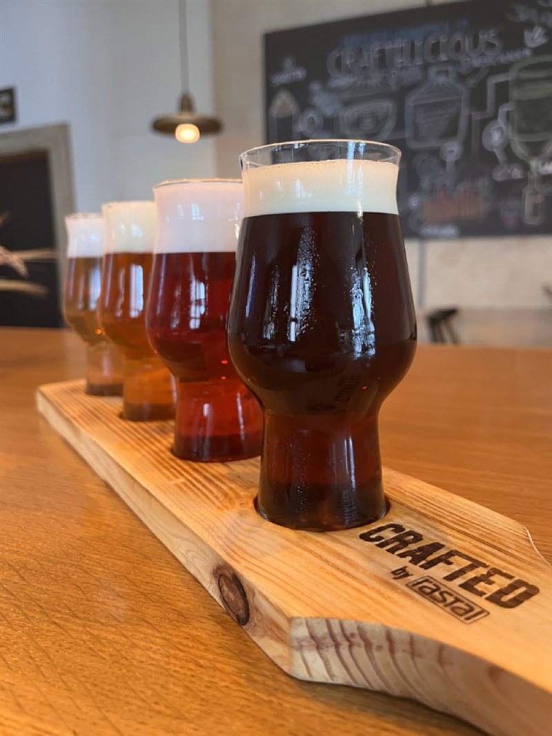 Tastingbrett mit vier Probiergläsern von hell bis dunkel auf dem Holztisch